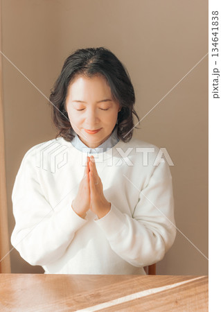 自宅で故人に祈りを捧げるミドル女性 134641838