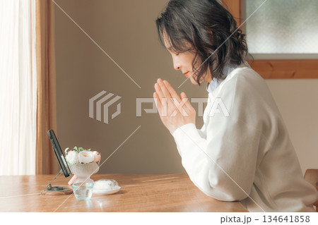 自宅で故人に祈りを捧げるミドル女性 134641858