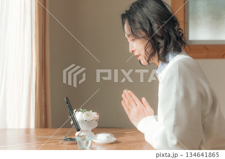 自宅で故人に祈りを捧げるミドル女性 134641865