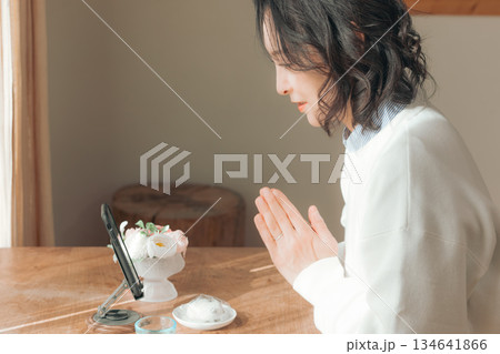 自宅で故人に祈りを捧げるミドル女性 134641866