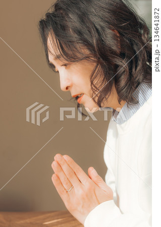 自宅で故人に祈りを捧げるミドル女性 134641872