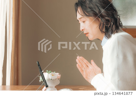 自宅で故人に祈りを捧げるミドル女性 134641877