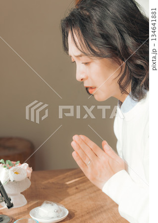 自宅で故人に祈りを捧げるミドル女性 自宅で故人に祈りを捧げるミドル女性 134641881
