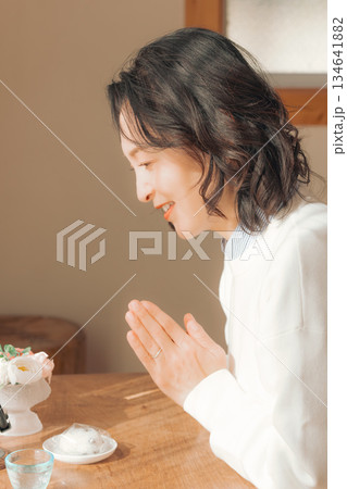 自宅で故人に祈りを捧げるミドル女性 134641882