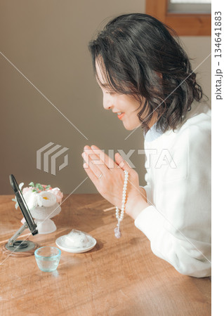 自宅で故人に祈りを捧げるミドル女性 自宅で故人に祈りを捧げるミドル女性 134641883