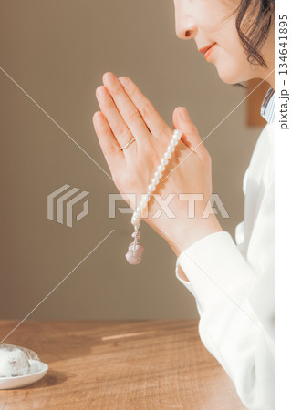 自宅で故人に祈りを捧げるミドル女性 134641895