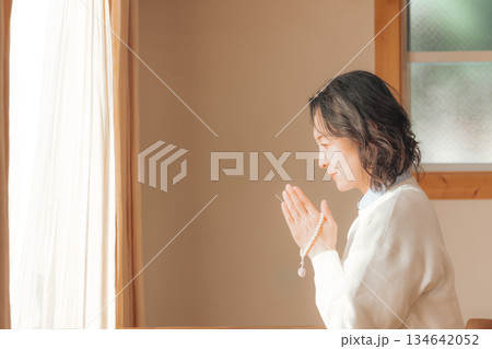 自宅で故人に祈りを捧げるミドル女性 自宅で故人に祈りを捧げるミドル女性 134642052
