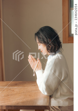 自宅で故人に祈りを捧げるミドル女性 134642054