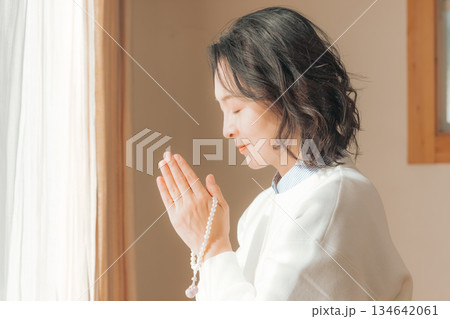 自宅で故人に祈りを捧げるミドル女性 自宅で故人に祈りを捧げるミドル女性 134642061
