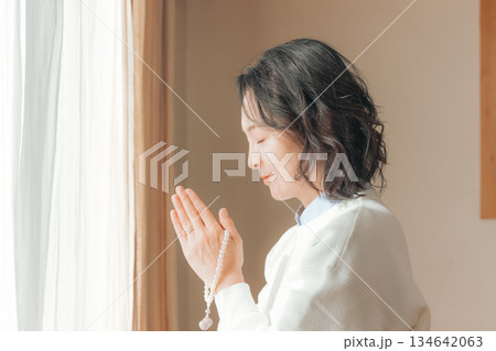 自宅で故人に祈りを捧げるミドル女性 134642063