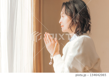 自宅で故人に祈りを捧げるミドル女性 134642065