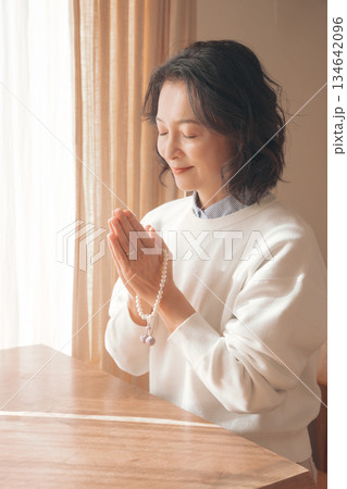 自宅で故人に祈りを捧げるミドル女性 134642096