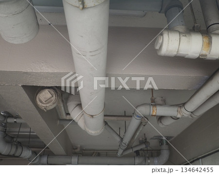 マンション1階駐車場の天井に配された、複雑な配管とダクトのインダストリアルな風景 134642455