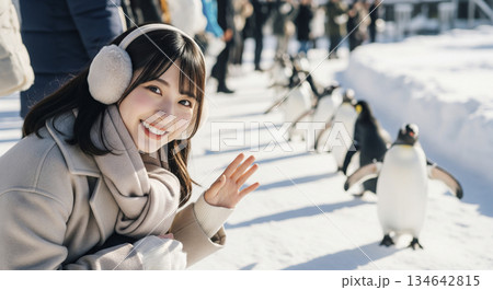 動物園でペンギンのパレードを眺めている女性 動物園でペンギンのパレードを眺めている女性 134642815