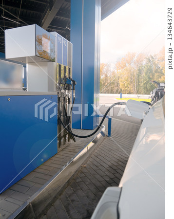 White car refuels at modern gas station with blue pump. Fueling vehicle energy demand and transportation concept. White car refuels at modern gas station with blue pump. Fueling vehicle energy demand and transportation concept. 134643729