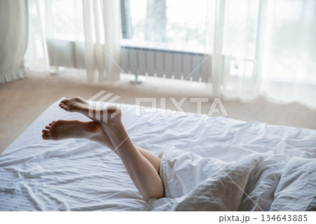 Female feet in bed. Young woman with beautiful legs in bedroom Female feet in bed. Young woman with beautiful legs in bedroom 134643885