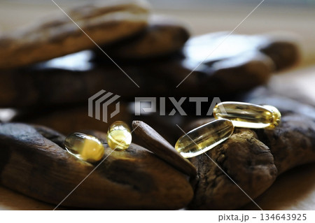 Golden omega 3 pills laying on a rustic wooden surface. Natural health supplement concept for wellness and nutrition. Golden omega 3 pills laying on a rustic wooden surface. Natural health supplement concept for wellness and nutrition. 134643925