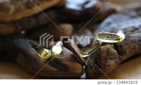 Cod liver oil capsules for health supplement. Omega 3 fatty acid pills on driftwood for natural wellness. Healthy diet and nutrition concept. Cod liver oil capsules for health supplement. Omega 3 fatty acid pills on driftwood for natural wellness. Healthy diet and nutrition concept. 134643929