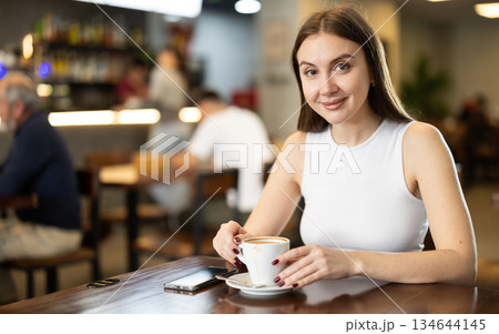 Girl whiles away time and drink coffee in cafe Girl whiles away time and drink coffee in cafe 134644145