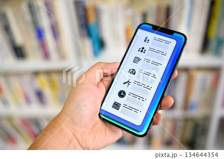 本棚前でスマホ操作 本棚前でスマホ操作 134644354