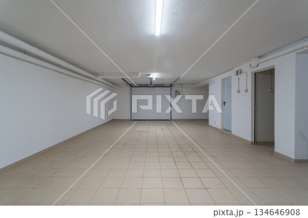 This garage features ample space with clean, tiled floors and bright lighting. Ideal for parking vehicles or storing belongings in a residential area This garage features ample space with clean, tiled floors and bright lighting. Ideal for parking vehicles or storing belongings in a residential area 134646908