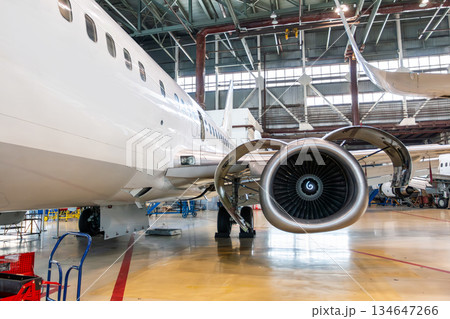 White passenger plane in the aircraft hangar. Airplane under maintenance. Checking mechanical systems for flight operations 134647266