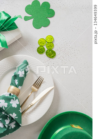 St Patricks day flat lay with green shamrock symbol and lucky coins on light background. Vertical format. Irish holiday decoration concept. 134649399