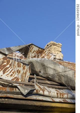bent steel roof on a village house, details of a house in a rural area with a primitive roof that was badly damaged, an abandoned house 134649592
