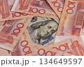 red Chinese money in denominations of one hundred yuan and American dollars , a pile of paper cash of American and Chinese money , Chinese banknotes of 100 yuan 134649597