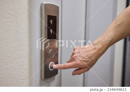 A Close Up Image of a Hand Passionately Pressing the Elevator Button in a Modern Building A Close Up Image of a Hand Passionately Pressing the Elevator Button in a Modern Building 134649621