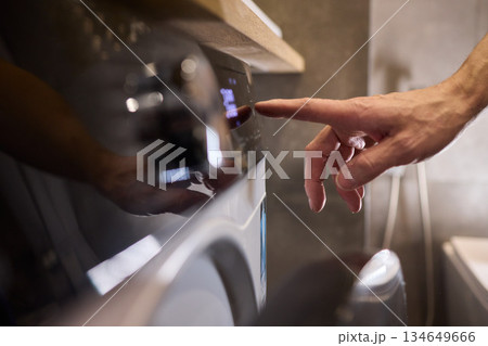 Individual Interacting with a Modern Washing Machines Control Panel for Efficient Laundry Tasks Individual Interacting with a Modern Washing Machines Control Panel for Efficient Laundry Tasks 134649666