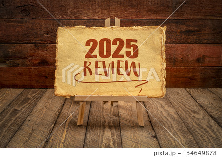 2025 year review - easel sign with antique paper against rustic wood, end of year business concept 134649878