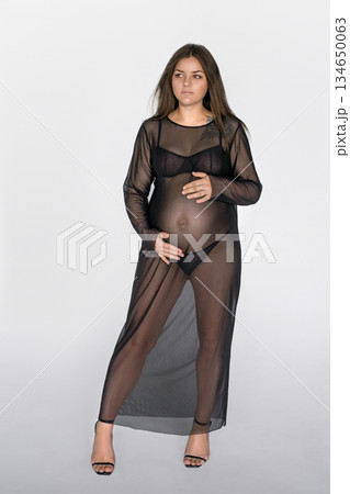 Beautiful stylish delicate pregnant woman in a black long transparent dress Beautiful stylish delicate pregnant woman in a black long transparent dress 134650063