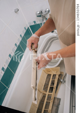 Vertical cropped shot of man cleaning dirty air conditioner filter in basin filled with detergent, ensuring proper hygiene and air quality. Concept of air condition maintenance service repair Vertical cropped shot of man cleaning dirty air conditioner filter in basin filled with detergent, ensuring proper hygiene and air quality. Concept of air condition maintenance service repair 134650764