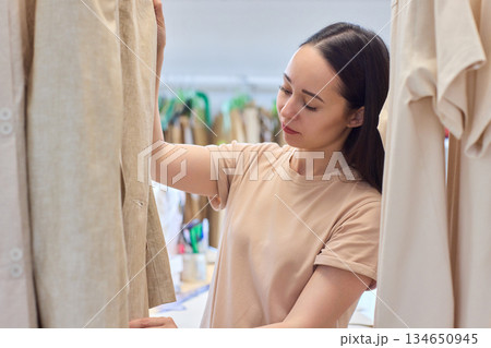 A Fashion Designer Carefully Organizing Beautiful and Elegant Dresses in Their Studio Workspace 134650945