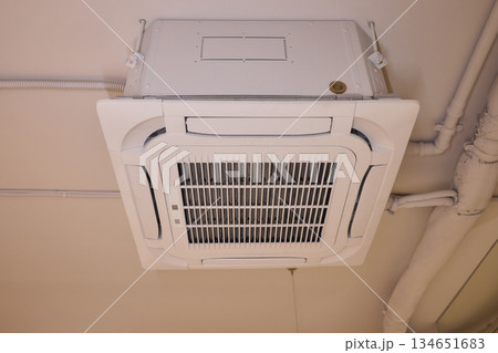 Interior air handling components view, Ceiling mounted air conditioning and ventilation setup, Commercial building HVAC infrastructure with technician inspection scene 134651683