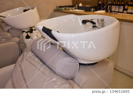 Salon wash station, Elegant hair wash station setup, Modern glossy porcelain hair washing basin setup, Sterile bright salon with professional hair washing and treatment area Salon wash station, Elegant hair wash station setup, Modern glossy porcelain hair washing basin setup, Sterile bright salon with professional hair washing and treatment area 134651695