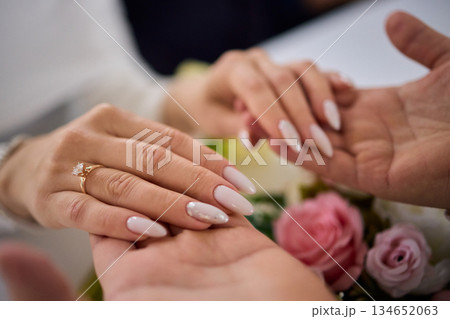 Wedding rings and roses exchange, Intimate moment with rings and blooming flowers, Capturing tender exchange of wedding rings alongside bouquet of pink roses in warm Wedding rings and roses exchange, Intimate moment with rings and blooming flowers, Capturing tender exchange of wedding rings alongside bouquet of pink roses in warm 134652063
