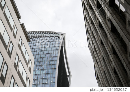 Modern Glass Skyscraper Framed by Historic Stone Buildings in City Architecture Modern Glass Skyscraper Framed by Historic Stone Buildings in City Architecture 134652087