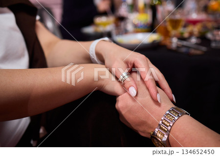 Friendly hand interlock, Close friends linked hands during joyful gathering, Intimate moment capturing friendship and reassurance with clasped hands during celebration 134652450