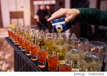 Vibrant party beverages, Festive setup with lively drink arrangements and busy bartenders, Array of layered shots and colorful cocktails ready for spirited gathering Vibrant party beverages, Festive setup with lively drink arrangements and busy bartenders, Array of layered shots and colorful cocktails ready for spirited gathering 134652502