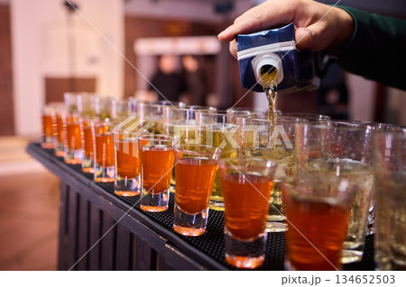 Vibrant party beverages, Festive setup with lively drink arrangements and busy bartenders, Array of layered shots and colorful cocktails ready for spirited gathering Vibrant party beverages, Festive setup with lively drink arrangements and busy bartenders, Array of layered shots and colorful cocktails ready for spirited gathering 134652503
