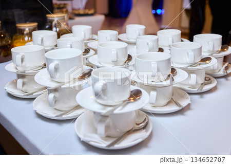 Elegant table setting, Refined display of fine china for celebration occasion, Impeccably organized porcelain teacups and saucers prepared for elegant wedding celebration Elegant table setting, Refined display of fine china for celebration occasion, Impeccably organized porcelain teacups and saucers prepared for elegant wedding celebration 134652707