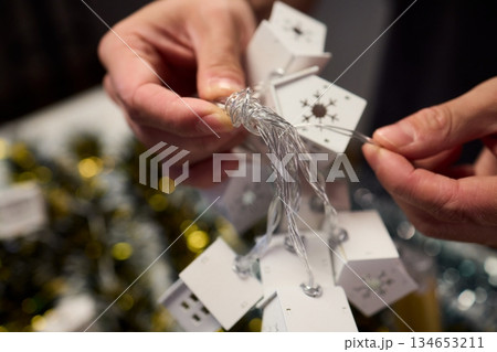Decorative festive scene, Intimate shot of illuminated cottages with festive accents, Careful arrangement of tiny fairy lights over pine garland and glowing cottages 134653211