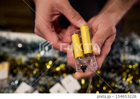 Technician assembling festive light string, Close view of hands installing holiday lighting, Focus on technician connecting string lights during festive preparations Technician assembling festive light string, Close view of hands installing holiday lighting, Focus on technician connecting string lights during festive preparations 134653226