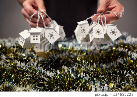 Decorative festive scene, Intimate shot of illuminated cottages with festive accents, Careful arrangement of tiny fairy lights over pine garland and glowing cottages 134653228