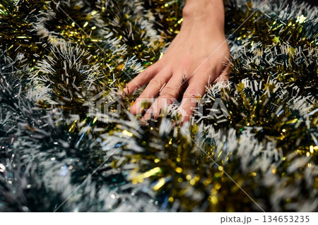 Closeup of hands preparing decorations, People arranging sparkling tinsel for celebration, Individuals meticulously position shimmering tinsel for seasonal festivity setup Closeup of hands preparing decorations, People arranging sparkling tinsel for celebration, Individuals meticulously position shimmering tinsel for seasonal festivity setup 134653235