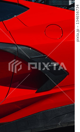 Bright red sports car highlighting sleek design and carbon fiber details in urban setting Bright red sports car highlighting sleek design and carbon fiber details in urban setting 134656734