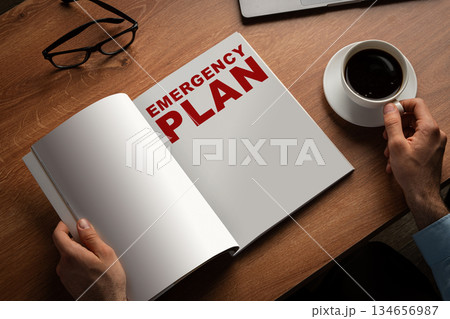 Creating a detailed emergency plan at a wooden desk with a cup of coffee 134656987