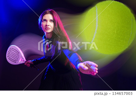 Woman playing tennis in dramatic lighting with a focus on a flying ball Woman playing tennis in dramatic lighting with a focus on a flying ball 134657003